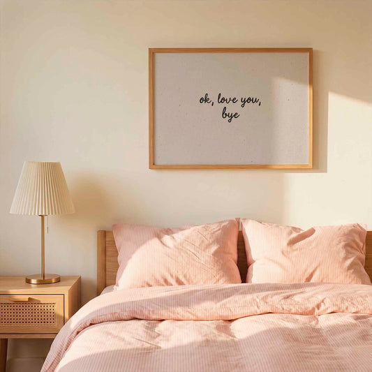 Bedroom with pink bedding, lamp, and framed artwork on the wall.