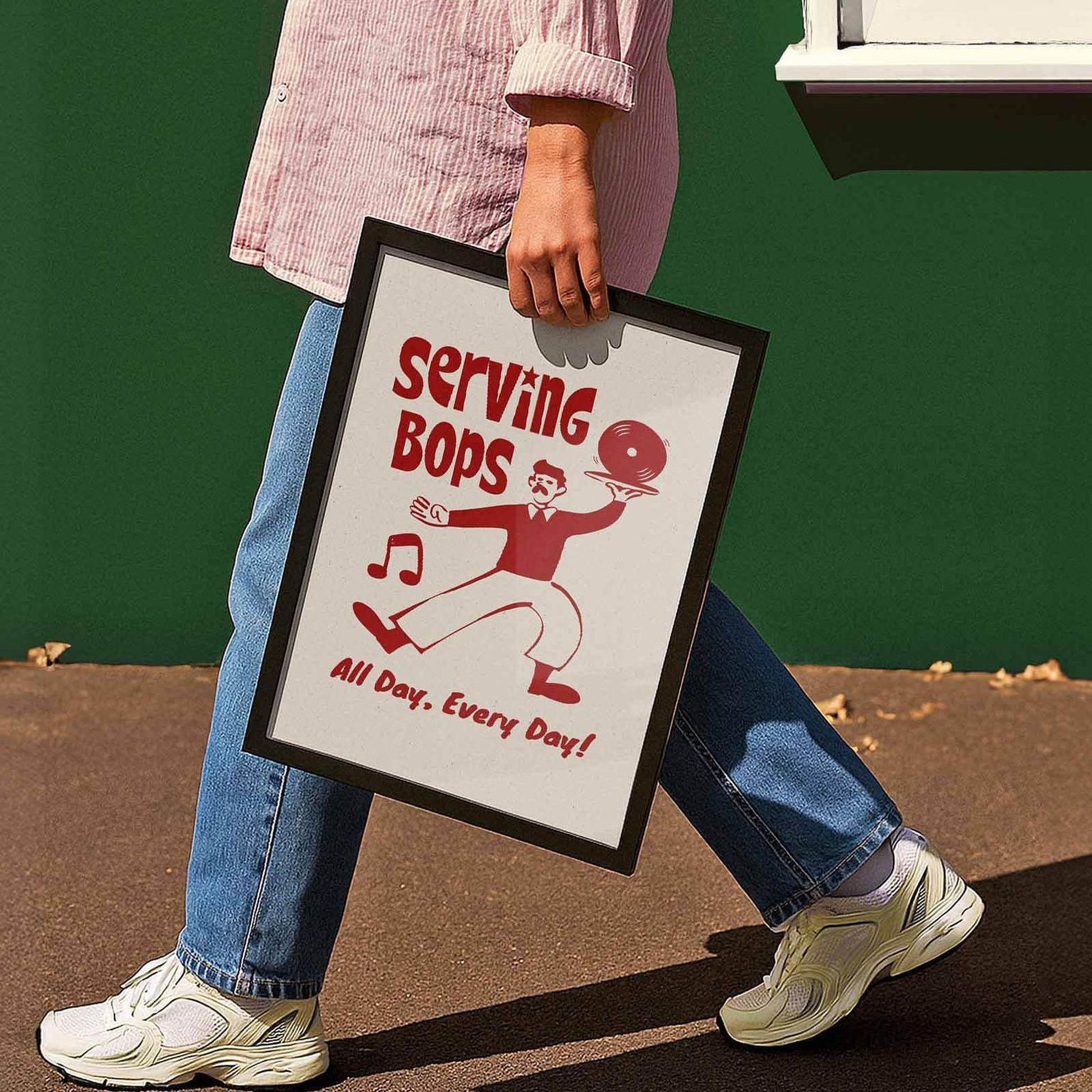 A person is walking while holding a framed sign that says "Serving Bops All Day, Every Day!"
