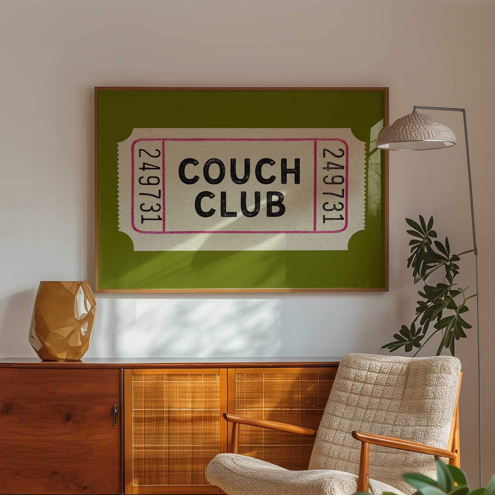 a living room with a large framed poster of a green ticket on the wall, a wooden cabinet, a beige armchair, and a potted plant.