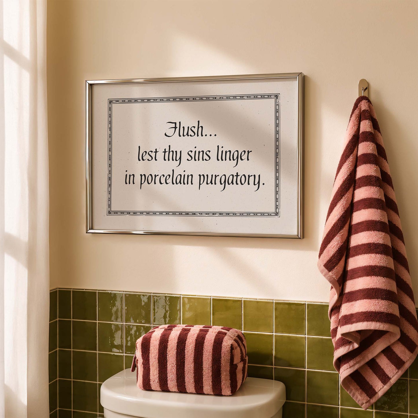 a bathroom with a framed quote on the wall above a toilet, a striped towel hanging on the wall, and a red and white striped bag on the toilet tank.