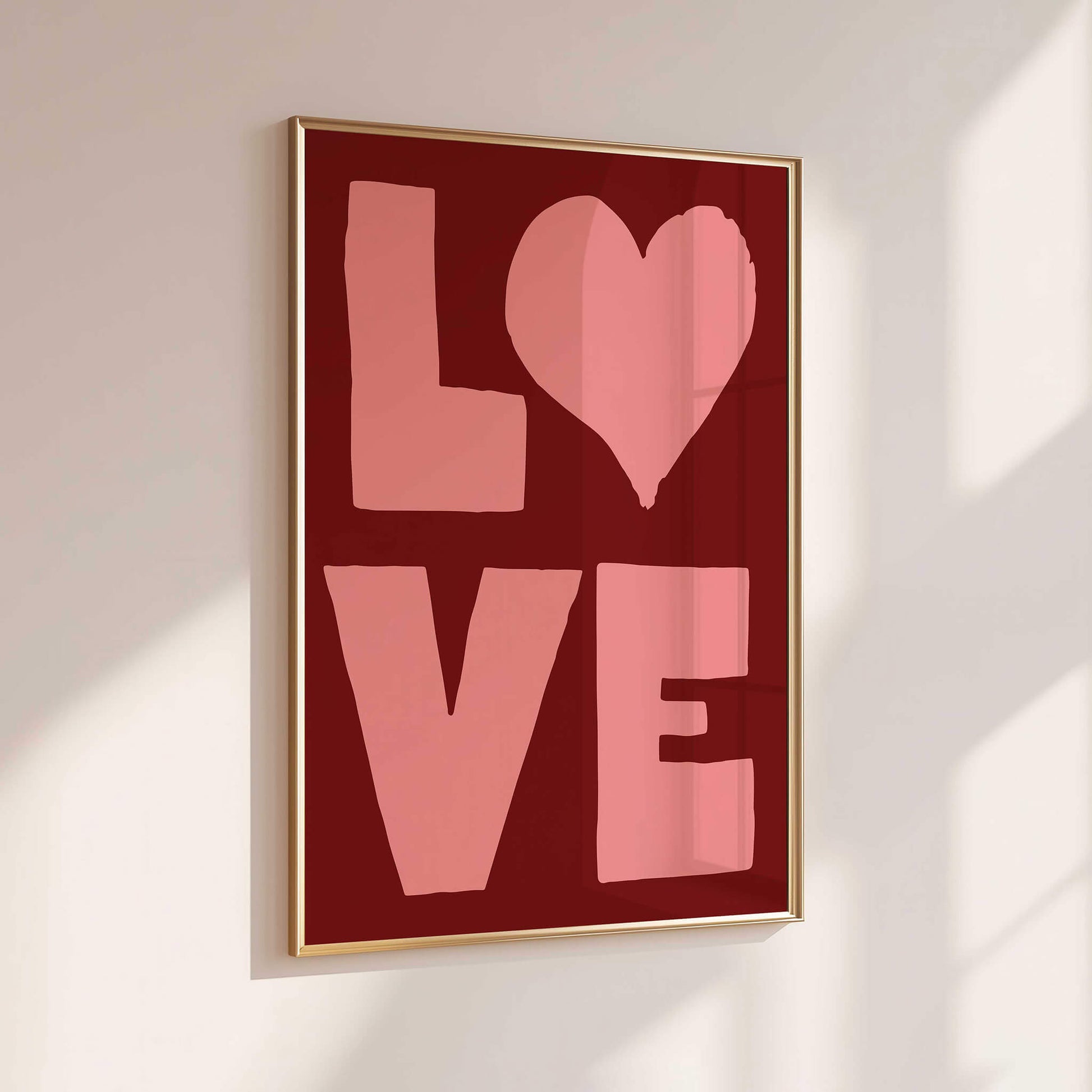A framed poster with the word "LOVE" in large pink letters against a red background.
