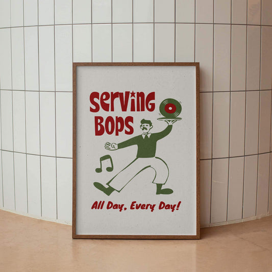 A framed poster with a cartoon illustration of a man holding a record album and a musical instrument, along with the text "Serving Bops All Day, Every Day!"